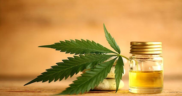 cbd oil in a bottle and marijuana leaf on 3 stones